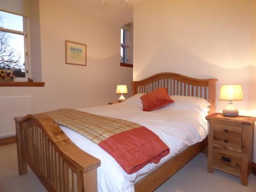 um quarto com uma cama de madeira e uma mesa de cabeceira com 2 candeeiros em The Pipers No 7 Lomond Castle em Balloch