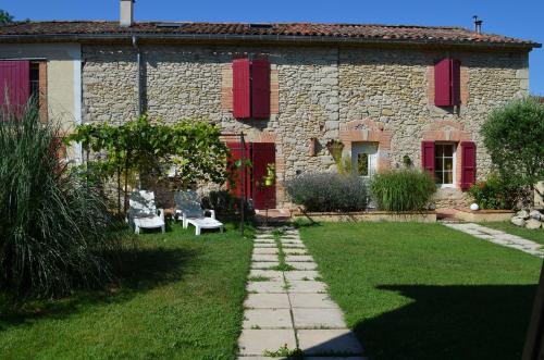 a stone house with red shutters and a yard at Les Treillettes in Puylaurens