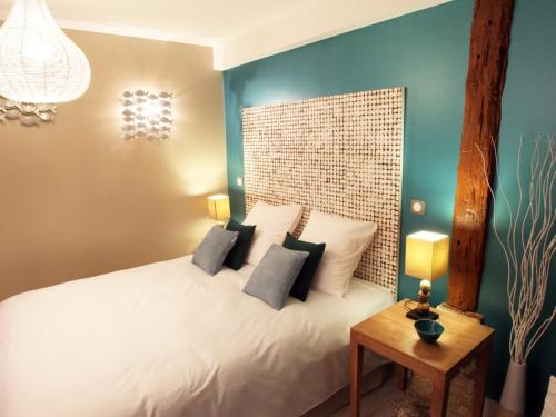 a bedroom with a white bed with a wooden headboard at Aux 5 Sens in Tillé