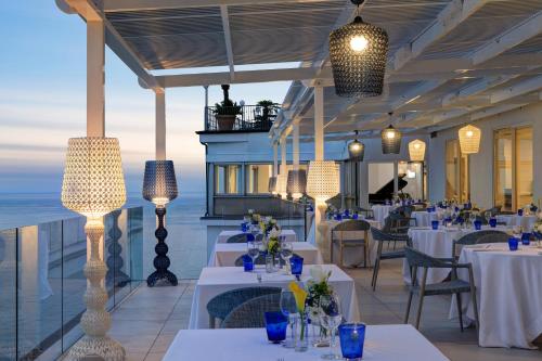a dining room table with chairs and umbrellas at Lloyd's Baia Hotel in Vietri sul Mare