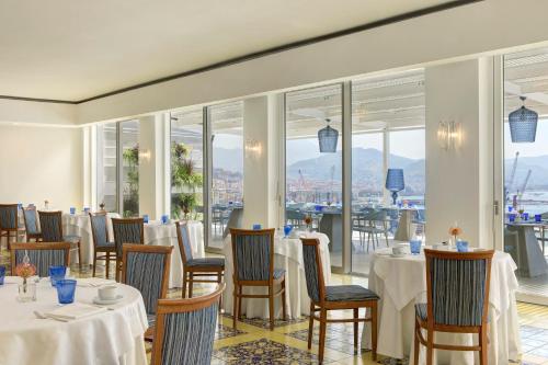 a restaurant with tables and chairs and windows at Lloyd's Baia Hotel in Vietri sul Mare