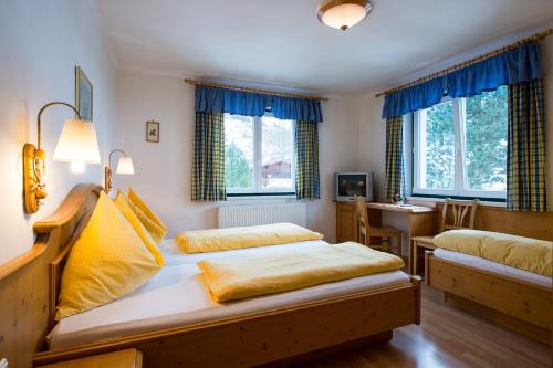 a bedroom with two beds and a table and windows at Annaberger Musikantenwirt in Annaberg im Lammertal