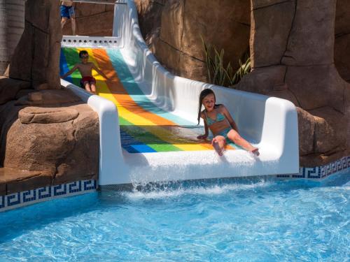 a little girl riding a water slide at a water park at Hotel Victoria Playa in Almuñécar