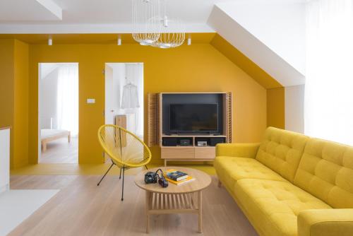 uma sala de estar com um sofá amarelo e uma televisão em Colors Apartments Zator - tylko 10 minut piechotą od Energylandii em Zator