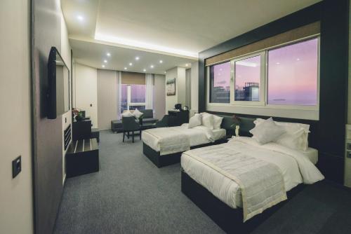 een hotelkamer met 2 bedden en een woonkamer bij Louis V Hotel Beirut in Beiroet