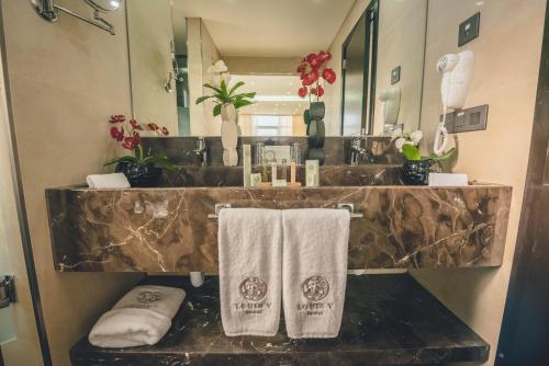 La salle de bains est pourvue d'un lavabo et de serviettes sur un comptoir. dans l'établissement Louis V Hotel Beirut, à Beyrouth
