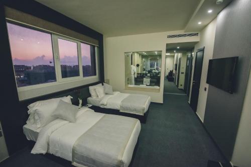 a hotel room with two beds and a flat screen tv at Louis V Hotel Beirut in Beirut