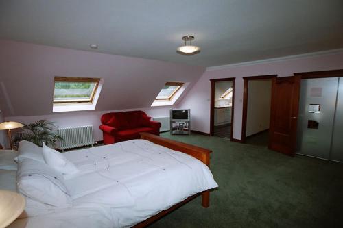 1 dormitorio con 1 cama blanca grande y 1 silla roja en Coachouse en Balloch