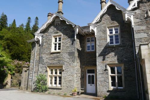 an old stone house with white windows at The Lake Lodge, Wansfell Holme, Windermere in Ambleside