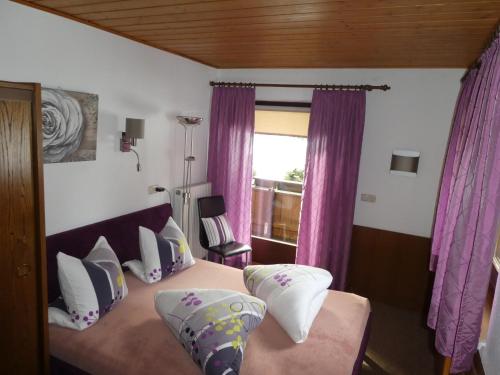 a bedroom with a bed with purple curtains and a window at Almblick Appartements in Sankt Jakob in Defereggen