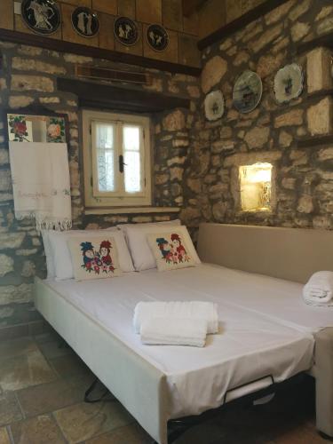 a large bed in a room with a stone wall at Casa Victoria in Katokhórion