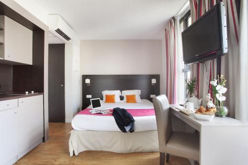 1 dormitorio con 1 cama y escritorio con TV en Odalys City Aix en Provence Les Floridianes en Aix-en-Provence