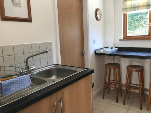 una cucina con lavandino e 2 sgabelli da bar di Windrush Apartment a Witney