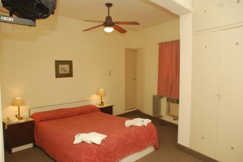 a bedroom with a red bed and a ceiling fan at Hotel Gran Crisol in Cordoba