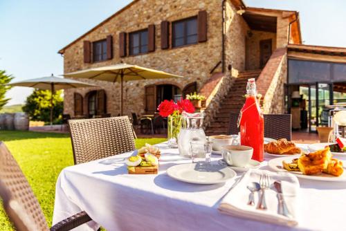 a table with food and drinks on it in front of a house at Agriturismo & Cantina Tenuta Casteani in Ribolla