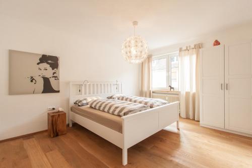 a white bedroom with a bed and a chandelier at Wohnen an der Juliuspromenade Main in Würzburg