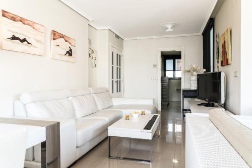 a white living room with a white couch and a tv at Gemelos 26 - Beninter All Inclusive in Benidorm