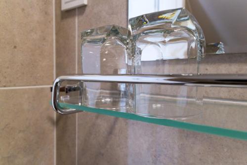 a glass shelf in a bathroom with two glasses on it at Airport room's Residence Garden in Velika Gorica
