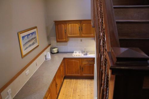 una pequeña cocina con armarios de madera y fregadero en Stables Lodge en Balloch