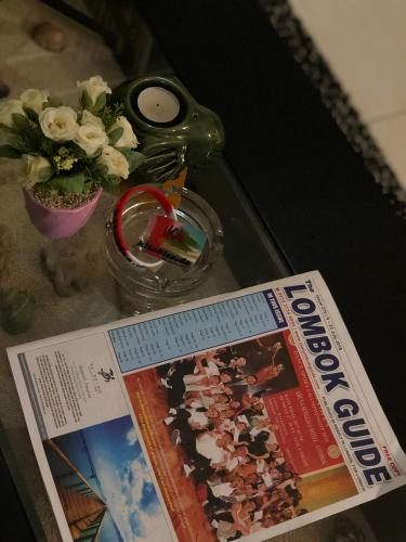 a magazine and a vase with flowers on a table at Fullhouse in Mataram