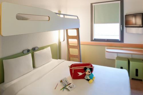 a bedroom with a bed with a doll in a suitcase at ibis Budget Brussels South Ruisbroek in Ruisbroek