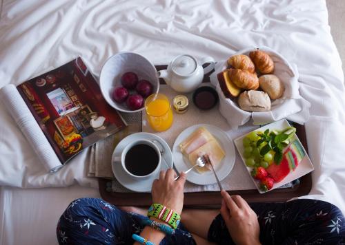 a person sitting on a bed with a tray of food at Hotel Meira in Vila Praia de Âncora