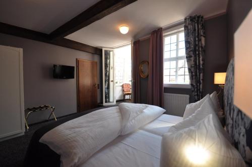 a bedroom with a large white bed with a window at Hotel Schmuckkästchen in Miltenberg
