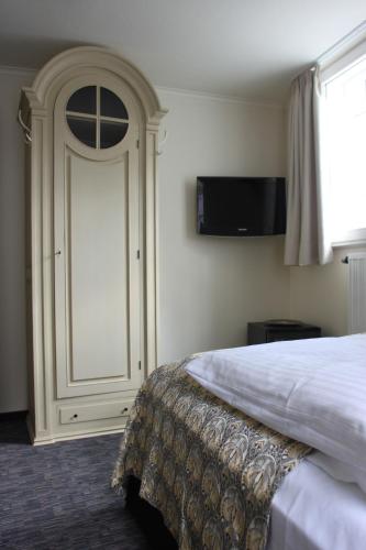 a bedroom with a bed and a door with a television at Hotel Schmuckkästchen in Miltenberg
