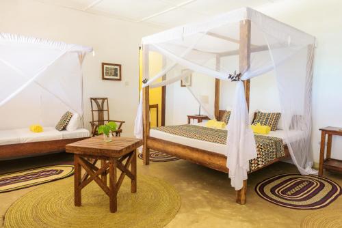 a bedroom with two beds with mosquito nets at Maji Lodge in Matemwe