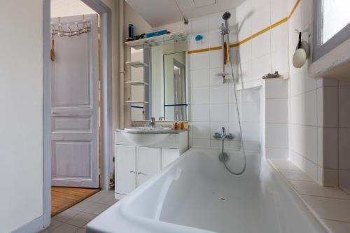Baño blanco con bañera y lavamanos en Veeve - Balcony Bliss, en París