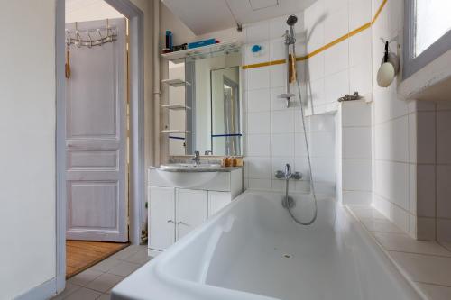 une salle de bain blanche avec une baignoire et un lavabo dans l'établissement Veeve - Balcony Bliss, à Paris