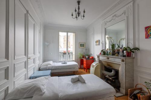- une chambre avec 2 lits, une cheminée et un miroir dans l'établissement Veeve - Balcony Bliss, à Paris