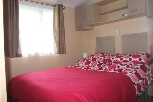 a bedroom with a bed with a pink blanket at The Valley Static Caravan in Pembrokeshire