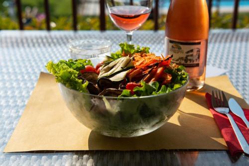 a bowl of salad on a table with a glass of wine at Agriturismo Il Giardino Degli Ulivi in Lazise