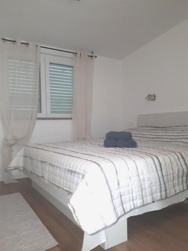 a white bedroom with a bed with a black bag on it at Kuća za odmor Pende in Banjol