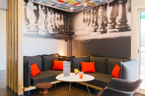 a room with a couch and a table with orange pillows at ibis Carcassonne Est la Cité in Carcassonne