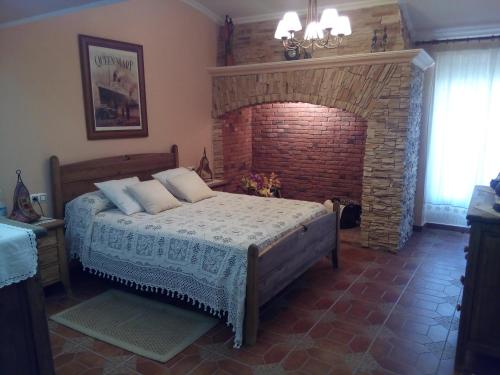 um quarto com uma cama e uma lareira de tijolos em Plaza del Pacifico La Bazana em Jerez de los Caballeros