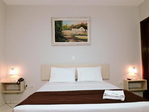 1 dormitorio con 1 cama con 2 lámparas y una foto en la pared en Londres Royal Hotel, en Londrina