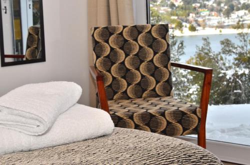 a chair sitting next to a bed with a window at Cabañas Agua Clara in Villa Pehuenia