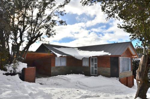 a house with snow on the roof in the snow at Cabañas Agua Clara in Villa Pehuenia
