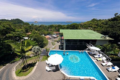 um resort com piscina e cadeiras e um edifício em El Faro Containers Beach Hotel em Manuel Antonio