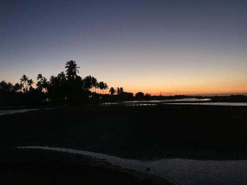 a sunset on a golf course with palm trees at Werala Beach Resort in Kalpitiya