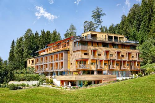 a large building on top of a hill with trees at Naturhotel Die Waldruhe GmbH in Chienes