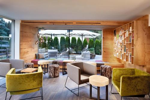 a room with chairs and tables and a large window at Naturhotel Die Waldruhe GmbH in Chienes