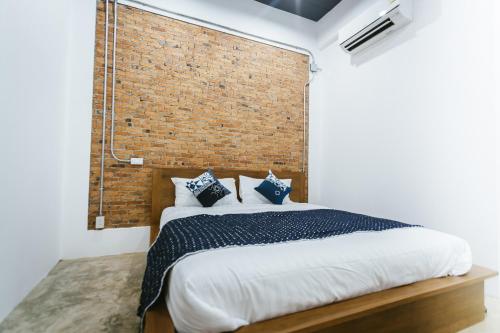 a bedroom with a large bed with a brick wall at Hug Inn Phrae in Phrae