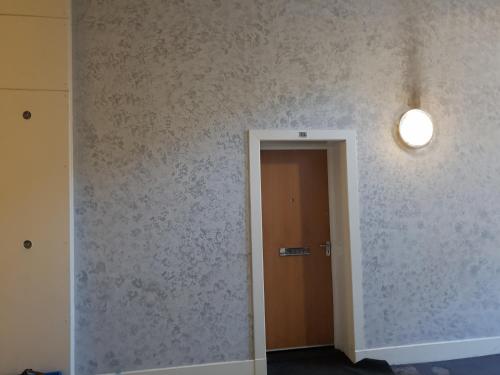 a hallway with a door and a light on a wall at Perfect Stay Near Glasgow Town in Glasgow