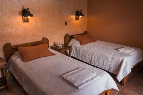 two beds in a hotel room with towels on them at La Escondida Hostal in Sucre