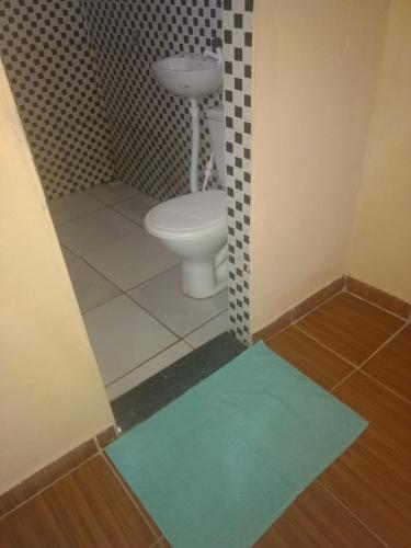 a bathroom with a toilet and a blue rug at Hospedagem Amanhecer in Barreirinhas