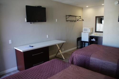 a hotel room with a desk and a tv on the wall at Beach Inn in Long Beach