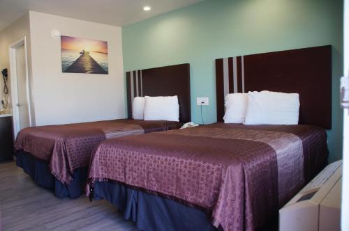 um quarto de hotel com duas camas com lençóis roxos em Beach Inn Motel em Long Beach
